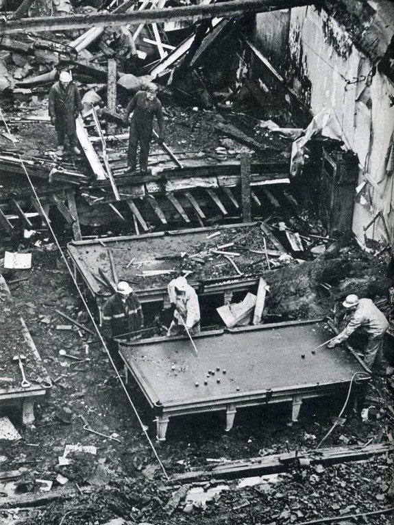 Photo noir et blanc historique montrant hommes jouant au billard parmi les décombres