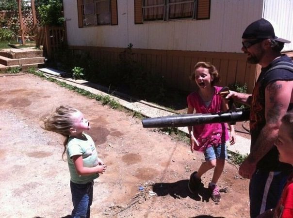 Trois enfants et une femme jouant avec une carabine à air comprimé dans une cour de maison