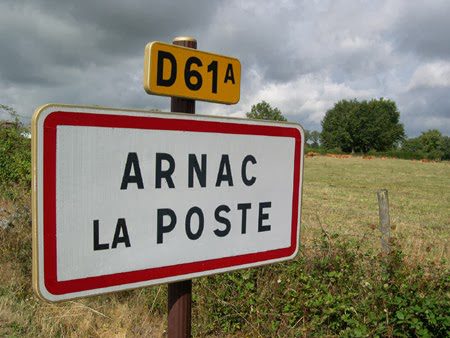 Panneau routier « Arnac La Poste » sur la route D61 avec champs en arrière-plan