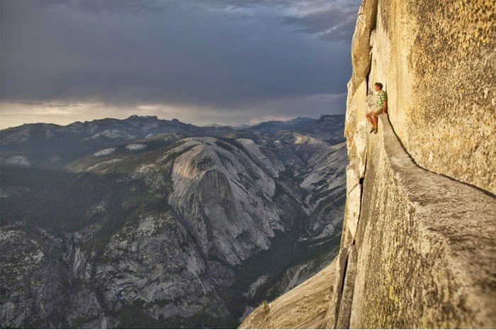 Grimpeur escaladant une paroi rocheuse vertigineuse surplombant des montagnes
