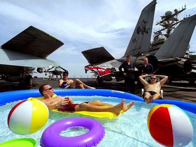 Soldats se relaxant dans une piscine gonflable avec ballons de plage, militaires en arrière-plan
