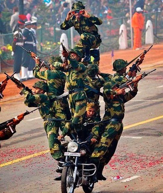 Soldats sur une moto avec armes levées lors d'un défilé militaire