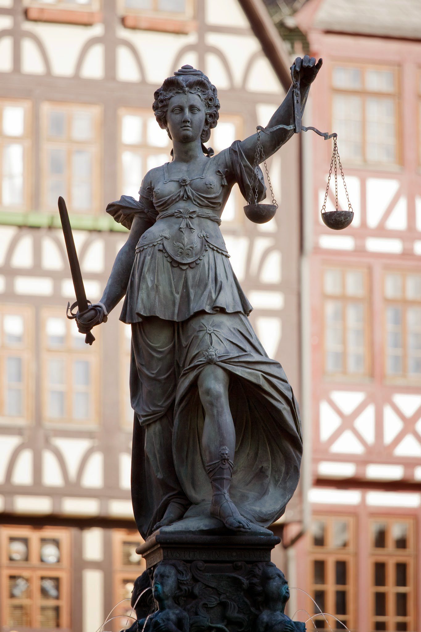 Statue de la Justitia en bronze tenant épée et balance devant immeuble ancien