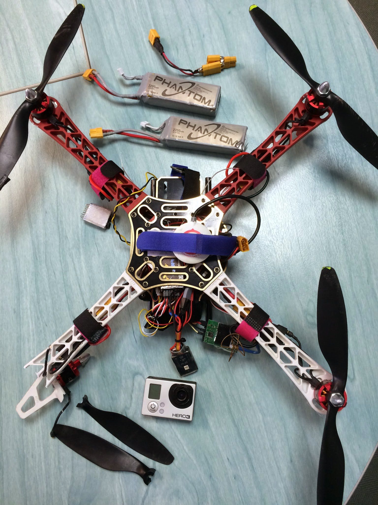 Drone démonté : moteurs avec hélices rouges, batteries Phantom et caméra GoPro