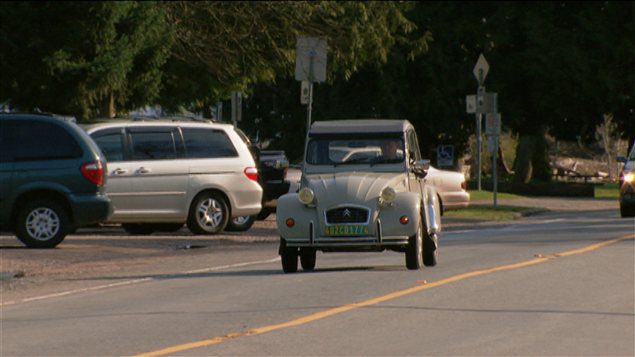 Citroën 2CV grise sur la route, véhicules modernes en arrière-plan
