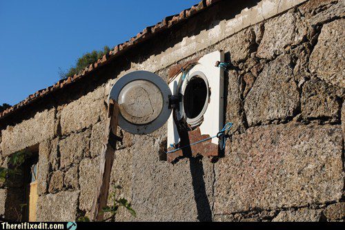 Hublot rouillé de fenêtre avec laveuse abandonnée au pied du mur