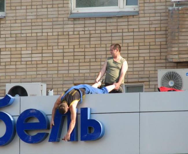 Acrobate en équilibre sur une lettre géante d'enseigne urbaine
