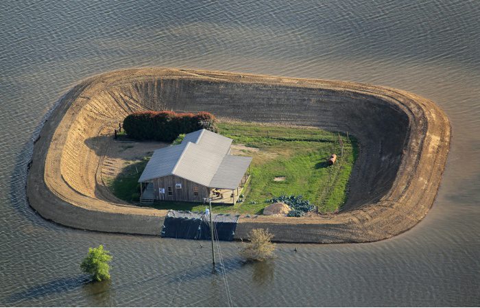 Maison blanche isolée sur une île entourée d'eau lors d'une inondation