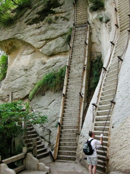 Personne montant des escaliers très raides construits à flanc de falaise rocheuse