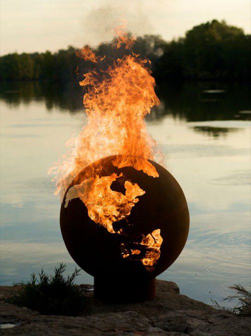 Boule noire incandescente projetant des flammes au bord d'une rivière