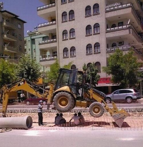 Pelleteuse de chantier passant au-dessus de personnes allongées sur le sol