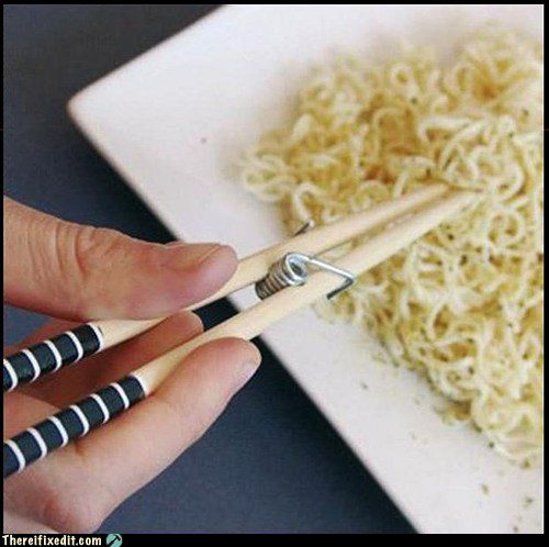 Baguettes chinoises et élastique servant de pince sur nouilles ramen, réparation absurde