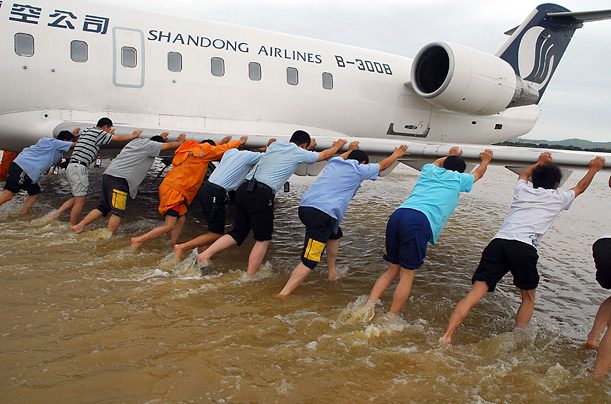 Groupe de personnes poussant dans l'eau un avion Shandong Airlines