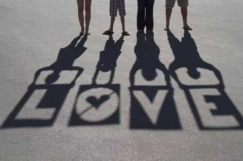 Quatre silhouettes projetant des ombres sur le sol formant le mot LOVE