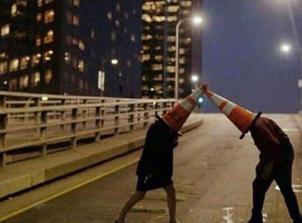 Deux personnages se battent avec des torches enflammées sur un pont urbain la nuit