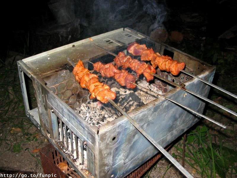 Gril barbecue de nuit avec brochettes orange cuisant sur braises