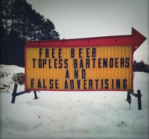 Panneau lumineux annonçant « Free beer, topless bartenders, false advertising »